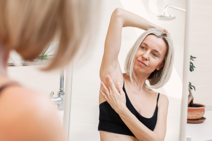 Middle Aged Woman Looking Herself In A Mirror While Doing Breast Self Examination